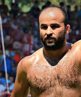 A shirtless male competitor in traditional Turkish oil wrestling raising his arm in victory. - Olive Oil Times