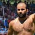 A shirtless male competitor in traditional Turkish oil wrestling raising his arm in victory. - Olive Oil Times