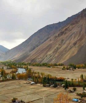A panoramic view of a mountainous landscape featuring fields and a river in the foreground. - Olive Oil Times