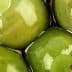 Close-up of green olives submerged in brine with a glossy surface. - Olive Oil Times