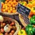 A display of various fresh vegetables and fruits including peppers, tomatoes, and eggplants in baskets. - Olive Oil Times