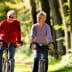 A man and woman riding bicycles side by side on a tree-lined path during daylight. - Olive Oil Times