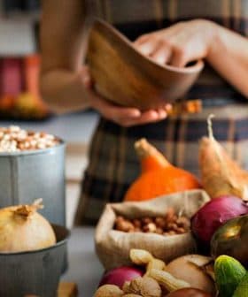 A variety of fresh vegetables and herbs displayed on a kitchen counter, including basil, onions, and peppers. - Olive Oil Times