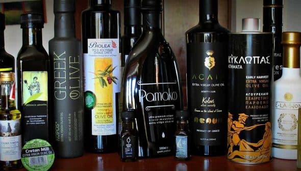 Various bottles of olive oil displayed on a shelf, featuring different brands and designs. - Olive Oil Times
