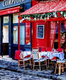 Outdoor café seating with tables and chairs arranged on a cobblestone street in Paris. - Olive Oil Times