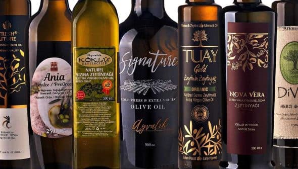 Assorted olive oil bottles displayed in a row with different labels and designs. - Olive Oil Times