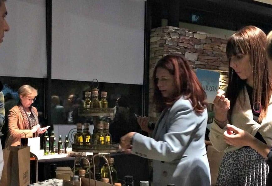 Group of individuals participating in an olive oil tasting event with various bottles displayed. - Olive Oil Times
