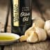 Bottle of garlic extra virgin olive oil next to garlic bulbs and a small dish of olive oil. - Olive Oil Times