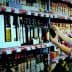 A woman examining a bottle of olive oil while shopping in a grocery store aisle filled with various oils. - Olive Oil Times