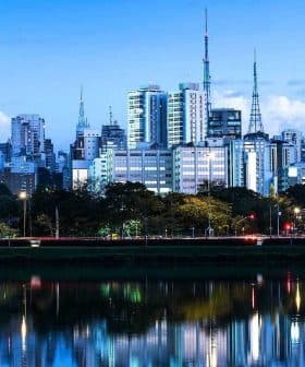 Cityscape of Sao Paulo featuring skyscrapers and reflections in water during dusk. - Olive Oil Times