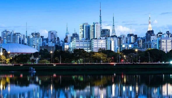 Cityscape of Sao Paulo featuring skyscrapers and reflections in water during dusk. - Olive Oil Times