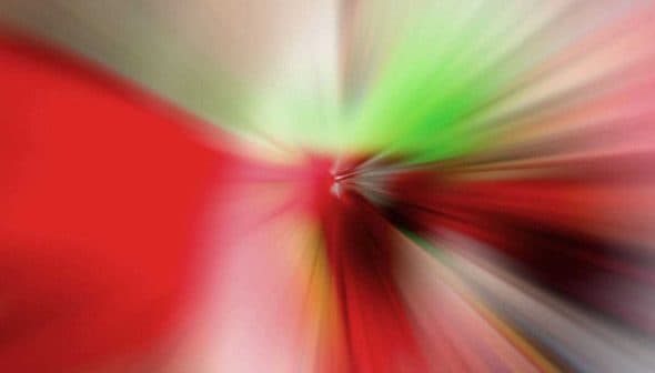 An abstract image featuring a colorful blur of red, green, and other colors radiating from a central point. - Olive Oil Times