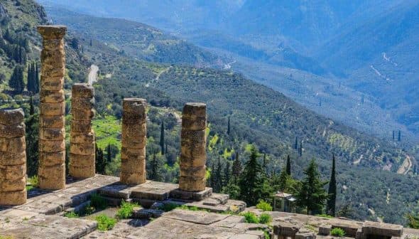 Stone columns of the ancient ruins at Delphi overlooking a mountainous landscape. - Olive Oil Times