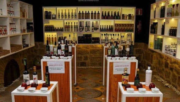 Interior view of an olive oil museum showcasing various bottles and products on display shelves. - Olive Oil Times