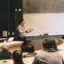 A speaker presenting in front of an audience in a classroom with a whiteboard. - Olive Oil Times