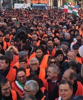 Large crowd of people wearing orange vests during a protest in an urban setting. - Olive Oil Times