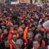 Large crowd of people wearing orange vests during a protest in an urban setting. - Olive Oil Times