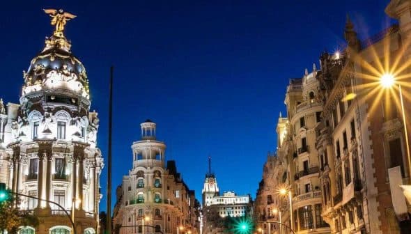 Night view of a cityscape in Madrid featuring illuminated buildings and streetlights. - Olive Oil Times