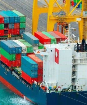 Cargo ship with colorful shipping containers docked at a port. - Olive Oil Times