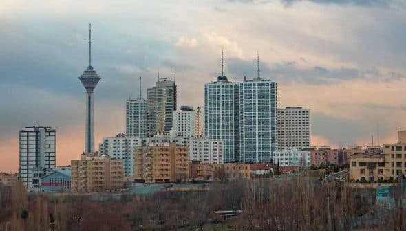 Cityscape of Tehran featuring the Milad Tower and various buildings under a cloudy sky. - Olive Oil Times