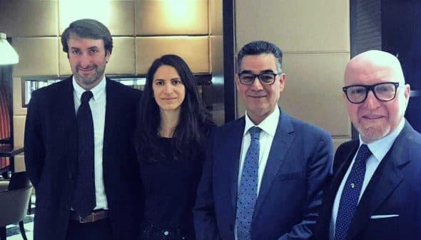 Four individuals in formal attire standing together in an indoor setting. - Olive Oil Times
