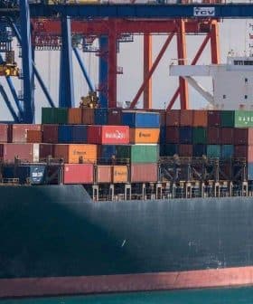 Container ship named Genoa loaded with colorful shipping containers at a port. - Olive Oil Times