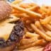 A cheeseburger with a slice of cheese and a side of French fries on a plate. - Olive Oil Times