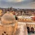View of a historic mosque dome with a cityscape of Cairo in the background during sunset. - Olive Oil Times