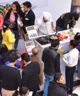 Group of people participating in an olive oil tasting event with various olive oil samples displayed. - Olive Oil Times