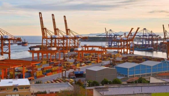 Container port in Piraeus, Athens with cranes and shipping containers along the waterfront. - Olive Oil Times