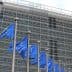 Multiple European Union flags displayed in front of a modern glass building. - Olive Oil Times