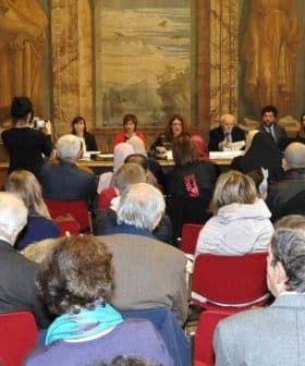 Audience seated in a hall during a literary event with speakers at the front. - Olive Oil Times