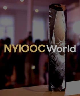 A crystal trophy with the inscription 'NYIOOC World' prominently displayed in a blurred background. - Olive Oil Times