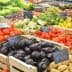 Assorted fresh vegetables displayed in wooden crates at a market stall, including tomatoes, cucumbers, and eggplants. - Olive Oil Times