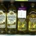 Various bottles of olive oil displayed on a supermarket shelf, including Filippo Berio and Colavita brands. - Olive Oil Times
