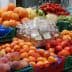 Assorted fresh fruits and vegetables displayed in crates at a market stall. - Olive Oil Times