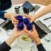 Four individuals toasting with blue glasses at a round table during a meeting. - Olive Oil Times