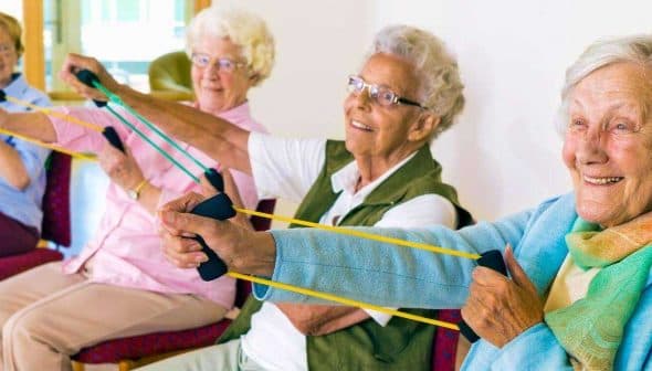 Four senior women using resistance bands for exercise in a seated position. - Olive Oil Times