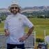 Chef wearing a white coat, hat, and sunglasses standing outdoors with a scenic background. - Olive Oil Times