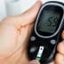Person holding a blood glucose meter displaying a reading of 5.9 mmol/L. - Olive Oil Times