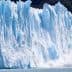 Large glacier with ice breaking off and falling into the water, creating a splash. - Olive Oil Times