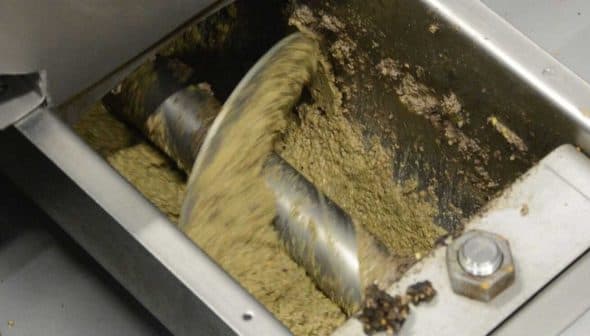 Inside view of an oil extraction machine showing mixing blades and oil paste. - Olive Oil Times