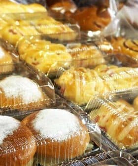 Various packaged bread products in clear plastic containers, including sweet rolls and pastries. - Olive Oil Times