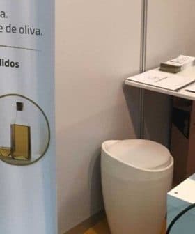 Olimaker machine for producing olive oil displayed at an event with informational banner. - Olive Oil Times