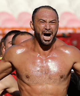 Group of enthusiastic fans celebrating at a sports event with one man prominently shouting. - Olive Oil Times