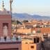 View of Marrakech cityscape featuring a prominent minaret and surrounding buildings under a clear sky. - Olive Oil Times