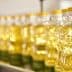Row of clear plastic bottles filled with vegetable oil on a production line. - Olive Oil Times