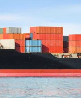 Large container ship with stacked colorful cargo containers on the deck in calm waters. - Olive Oil Times
