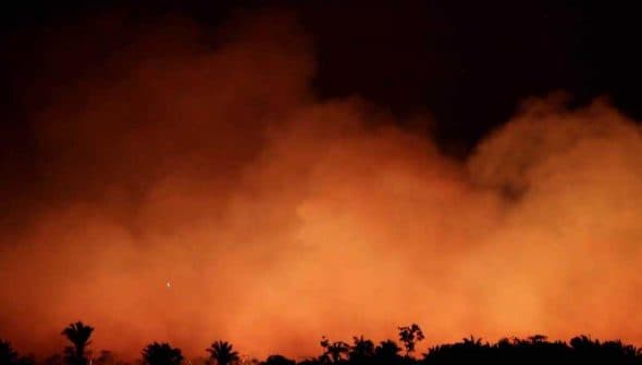 Thick smoke and flames rising in a dark environment, creating an orange glow. - Olive Oil Times