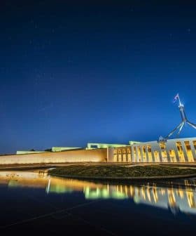 Night view of Parliament House in Canberra with reflections in the water. - Olive Oil Times
